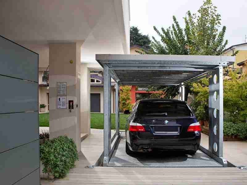 Sistema Montauto Senza Uomo a Bordo - Auto nera parcheggiata sotto struttura metallica grigia con tetto, in contesto residenziale con giardino